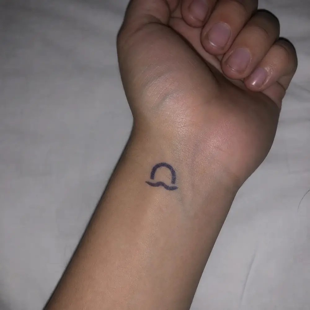 The original Foundry handout: deep blue-black ink stamp of an arch over a wave on Sigil's wrist